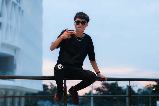 chlapec sedící na zábradlí ve městě s černým tričkem