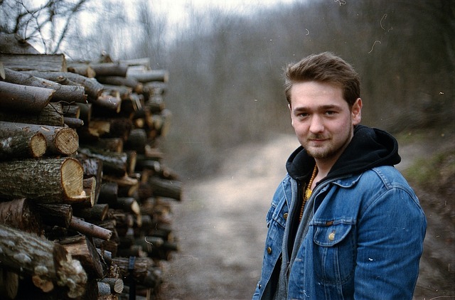 mladík u naskládaného dřeva u lesa